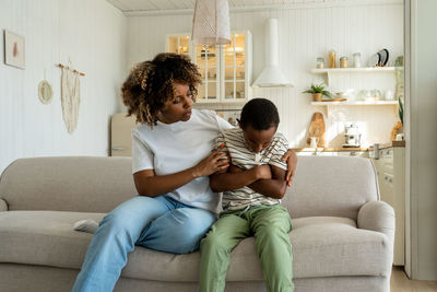 Mother and daughter sitting on sofa at home