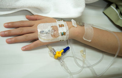 Cropped hand of patient wearing iv drip in hospital