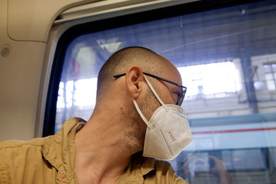 Close-up of man wearing mask looking away while sitting in train