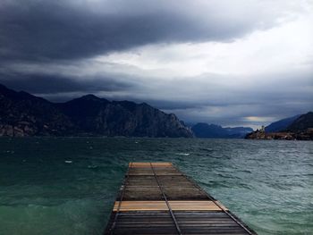Pier on sea against cloudy sky