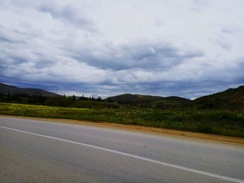 Road leading towards mountains against sky