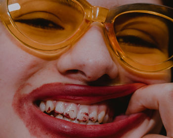 Close-up portrait of smiling young woman wearing sunglasses and lipstick