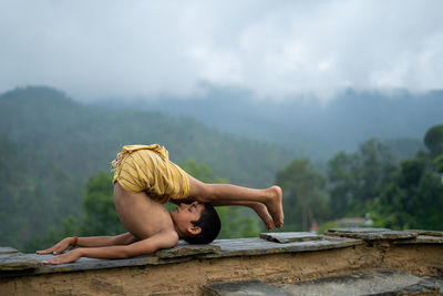 Man with arms outstretched against mountains against sky