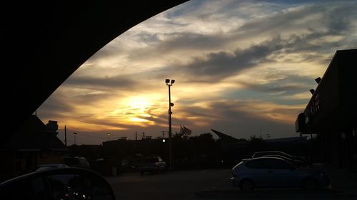 Cars on road against dramatic sky during sunset