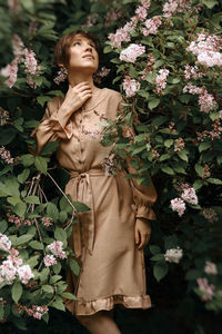 Beautiful young woman standing by flowering plants