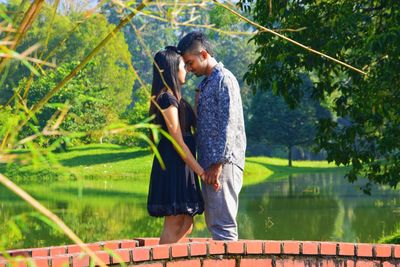 Side view of couple standing against trees