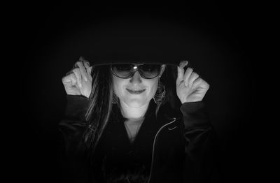 Portrait of smiling woman wearing hooded shirt against black background
