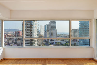 Living room with big windows and panoramic view to the district with modern buildings in barcelona