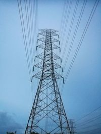 Low angle view of electricity pylon against blue sky