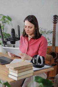 Portrait of young woman using digital tablet while sitting on table