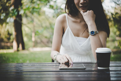 Midsection of woman using digital tablet at table