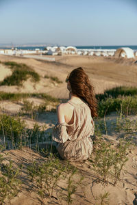 Rear view of woman sitting on beach