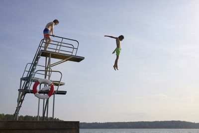 Teenage boys jumping into water from jumping tower