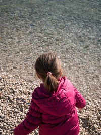 Rear view of girl wearing hooded shirt standing on sea shore at beach