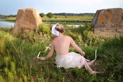 Shirtless woman sitting on land