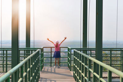 Rear view of woman standing by railing