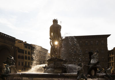 Low angle view of fountain against building in city against sky