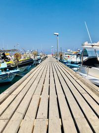 Sailboats moored at harbor against clear blue sky