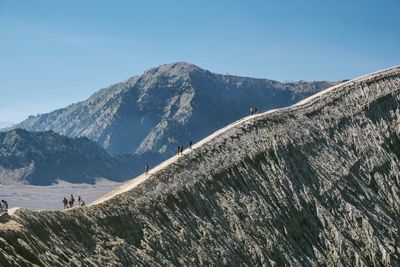 Scenic view of hikers on mountains against clear sky