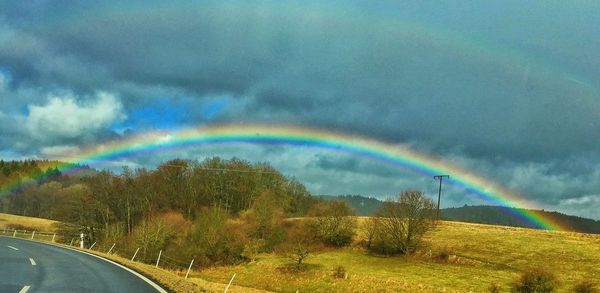 Rainbow over road against sky