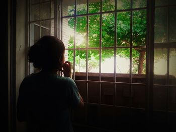 Rear view of man looking through window