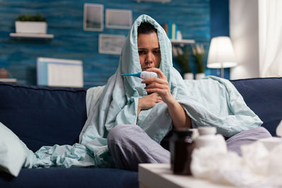 Midsection of man sitting on sofa at home