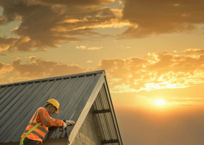 Rear view of man standing against sky during sunset