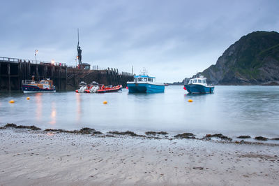 Sailboats moored on sea against sky