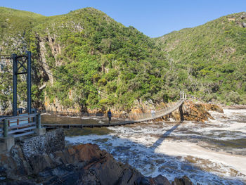 Scenic view of river by mountains against clear sky