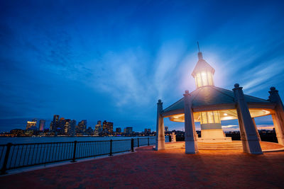 Illuminated building against cloudy sky at dusk