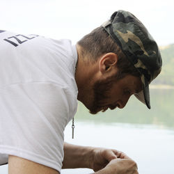 Side view of man wearing cap by lake