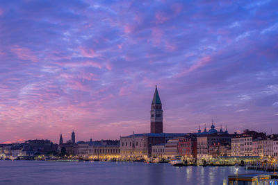 View of buildings at waterfront against cloudy sky