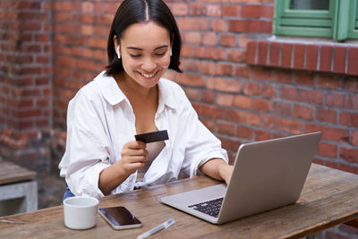 Young woman using laptop while sitting at table
