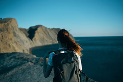 Rear view of woman standing by sea against clear sky