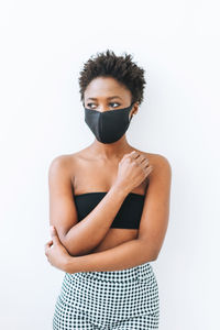 Beautiful young african american woman in black top and face mask isolated on the white 