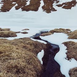 High angle view of snow covered land by lake