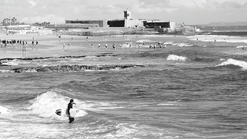 Man holding surfboard while standing in sea