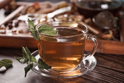 Cup of herbal mint tea with dry herbs on the tray.