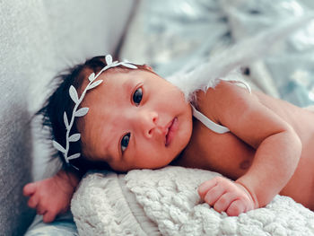 Portrait of cute baby lying on bed at home