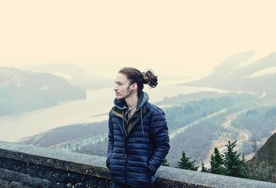 Young woman standing on mountain against sky during winter