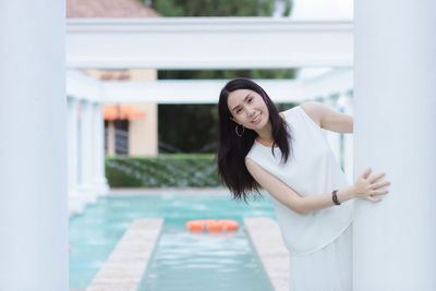 Portrait of smiling woman standing by swimming pool