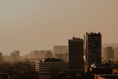 Buildings in city against clear sky during sunset