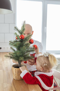 High angle view of cute girl playing with christmas tree at home