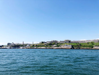 Sea by buildings against clear blue sky