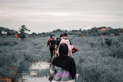 Rear view of people walking on field