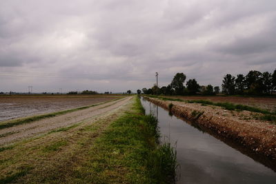 Road amidst field against sky