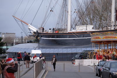 People at harbor against ship in city