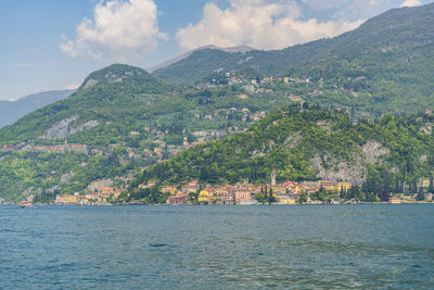 Scenic view of sea by mountain against sky