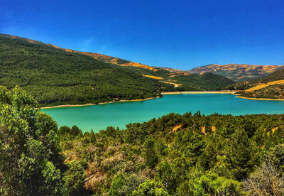 Scenic view of lake and mountains against blue sky