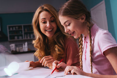 Cheerful mother and daughter discussing over studies
